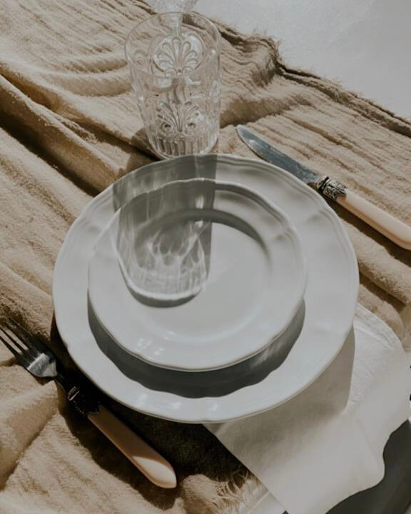 Mesa de almuerzo con platos blancos y luz de sol entrando por la ventana