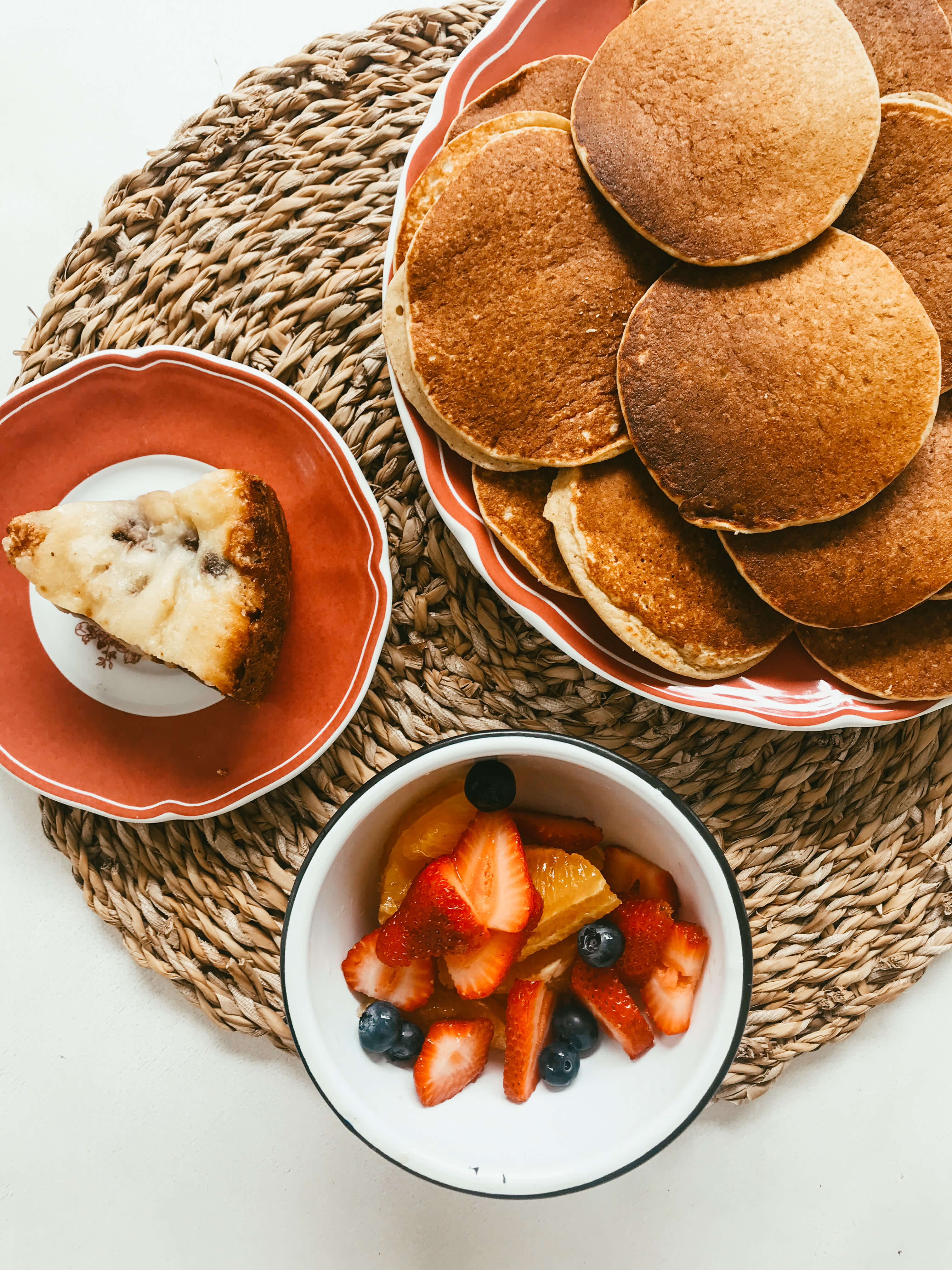 Desayuno con pancakes de banana, budín y bowl de frutas con naranjas, frutillas y arándanos