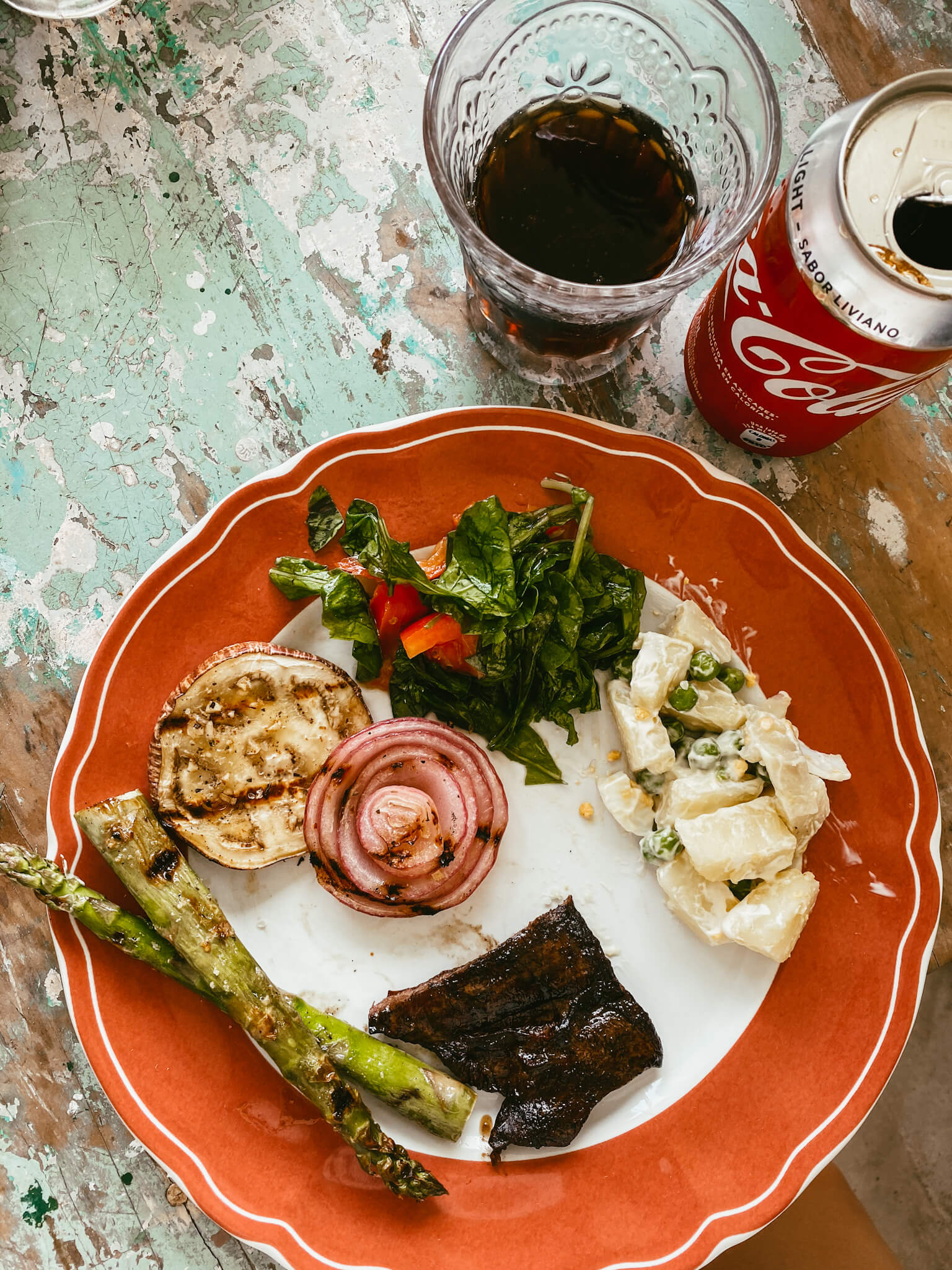 Plato con entraña, ensalada, verduras asadas, ensalada y un vaso de Coca Cola light