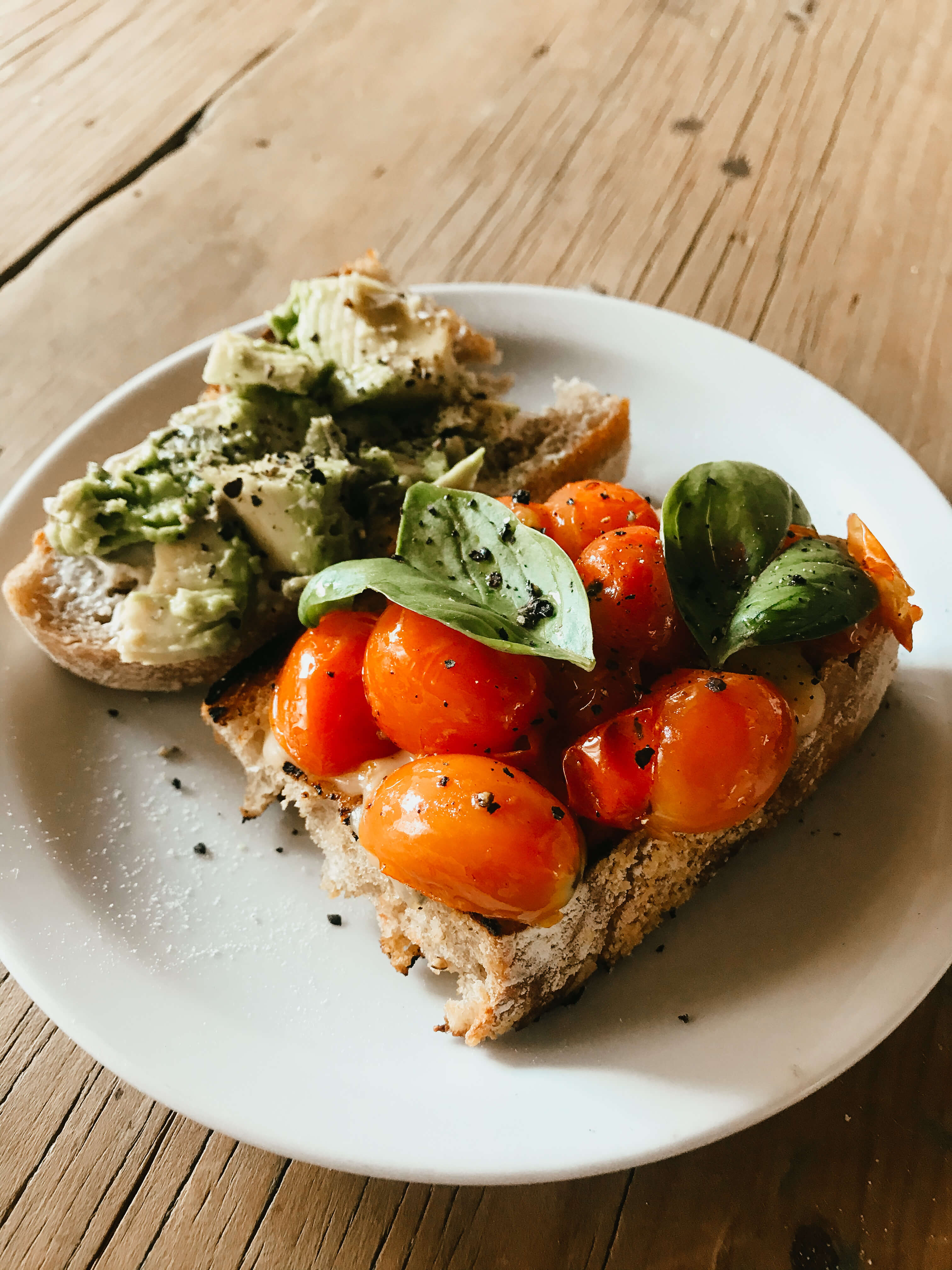 Una bruschetta de palta y una bruschetta de queso, cherrys y albahaca