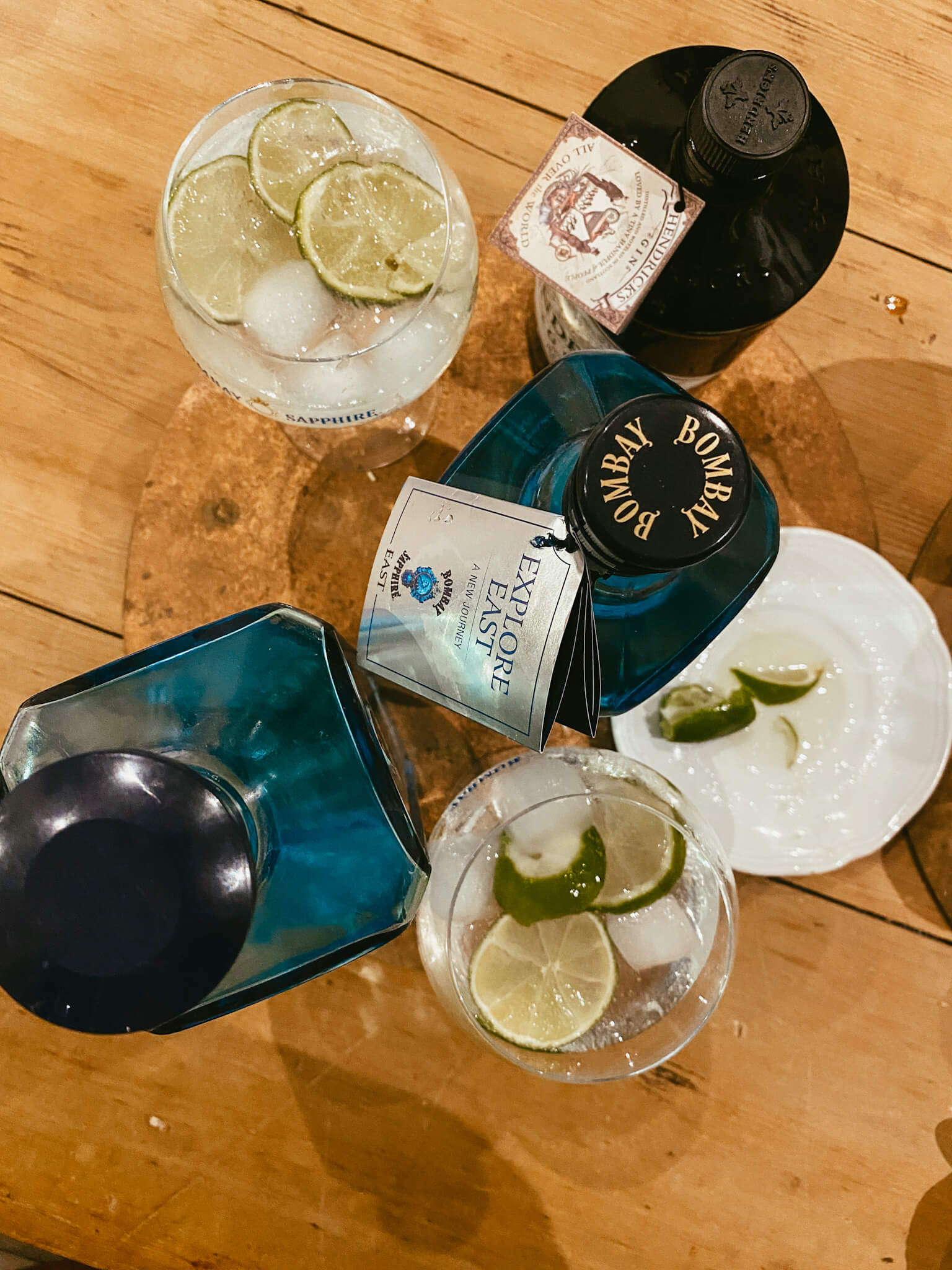 Copas de gin tonic con lima, botellas de Bombay y Hendricks