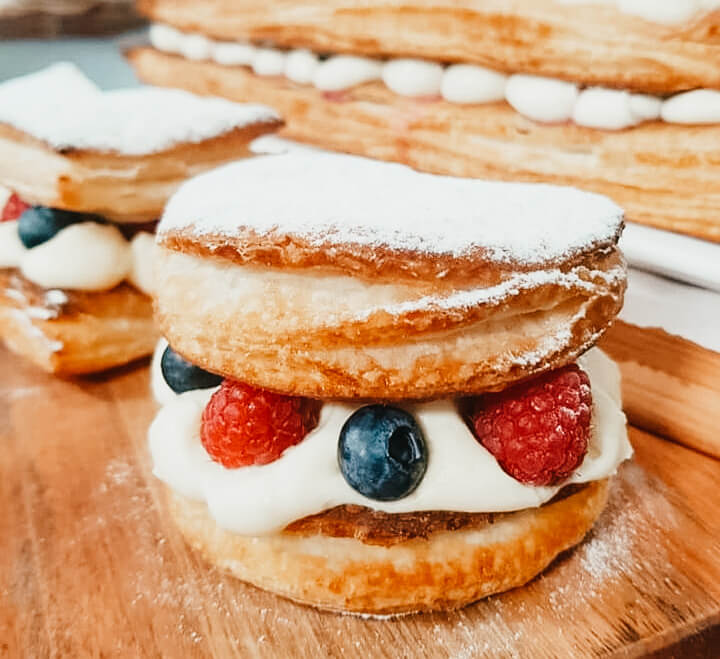 Mil hojas con relleno de crema pastestelera con crema chantilly y frutos rojos, espolvoreado con azúcar impalpable
